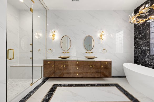 Luxurious bathroom with glass wall to shower, gold accent lighting and hardware and freestanding white tub.